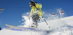 narciarz w trakcie zjazdu ze śniegiem pryskającym spod nart