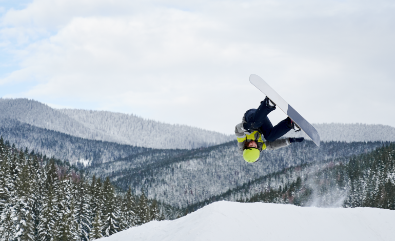 osoba robiąca trick podczas jazdy na snowboardzie