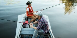 mężczyzna i chłopiec łowiący ryby z łódki za pomocą wędek