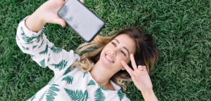 kobieta korzystająca z telefonu leżąc na trawie w swoim wolnym czasie